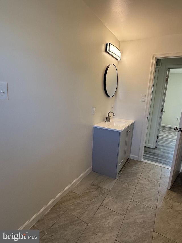 bathroom with marble finish floor, vanity, and baseboards