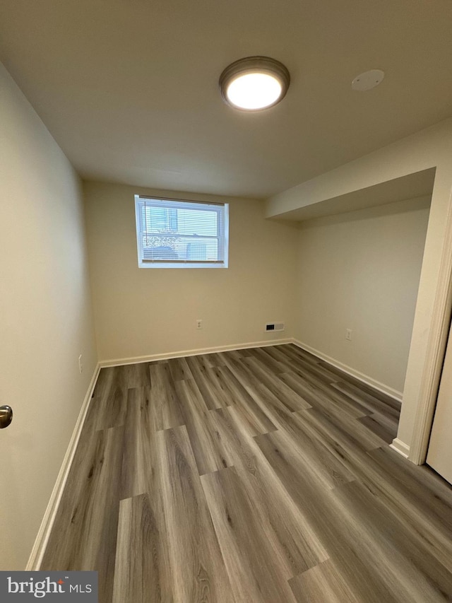 basement featuring wood finished floors, visible vents, and baseboards