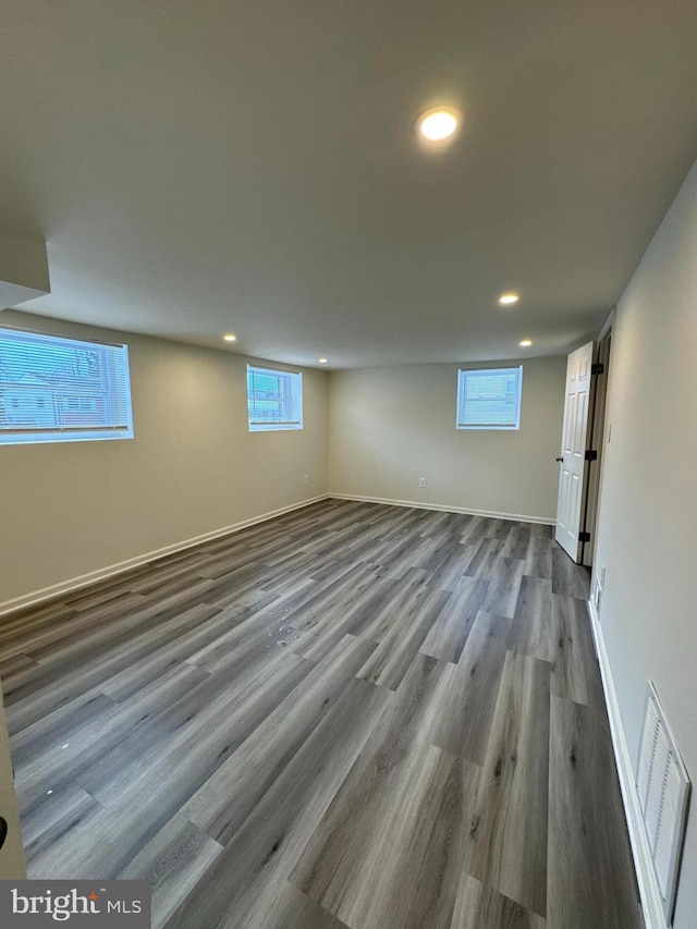 below grade area featuring baseboards, visible vents, wood finished floors, and recessed lighting