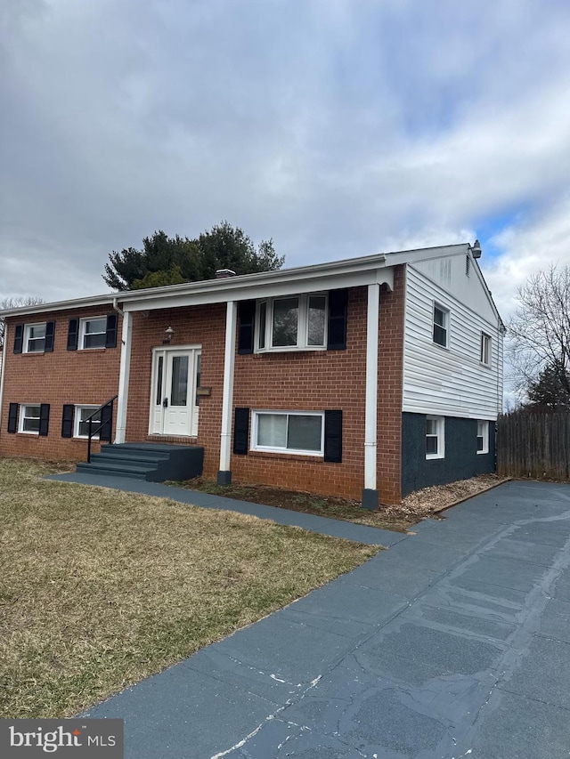 split foyer home with brick siding and fence