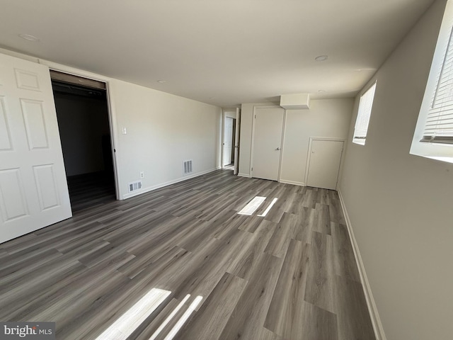 unfurnished bedroom featuring baseboards, visible vents, and wood finished floors