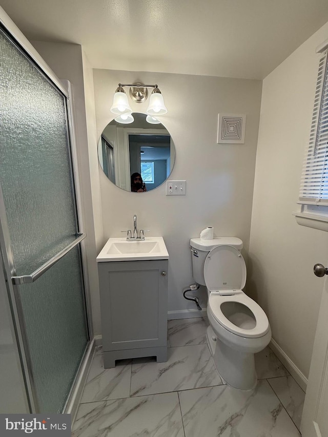 bathroom with baseboards, toilet, marble finish floor, vanity, and a shower stall