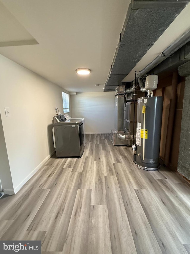 basement with heating unit, water heater, wood finished floors, washer and dryer, and baseboards