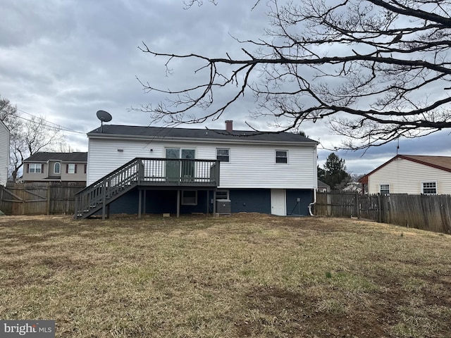 rear view of property with a lawn, a fenced backyard, a chimney, stairway, and a deck