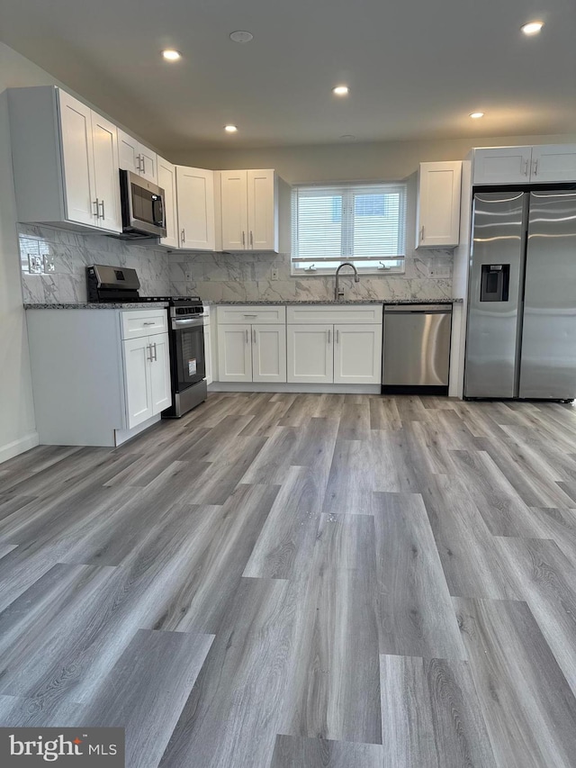 kitchen featuring a sink, stainless steel appliances, backsplash, and white cabinetry