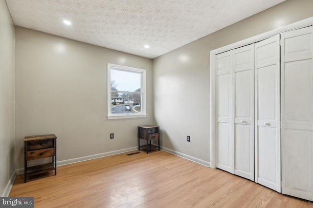 unfurnished bedroom with a closet, a textured ceiling, and light hardwood / wood-style flooring