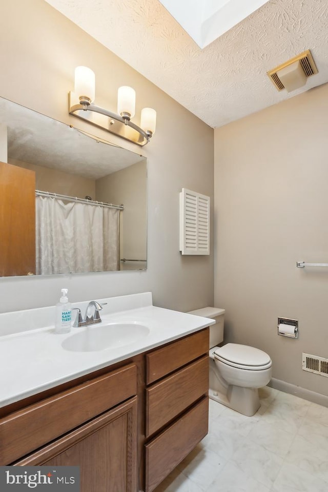 bathroom featuring vanity, toilet, and a textured ceiling