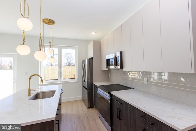 kitchen featuring tasteful backsplash, appliances with stainless steel finishes, light wood-style floors, a sink, and modern cabinets