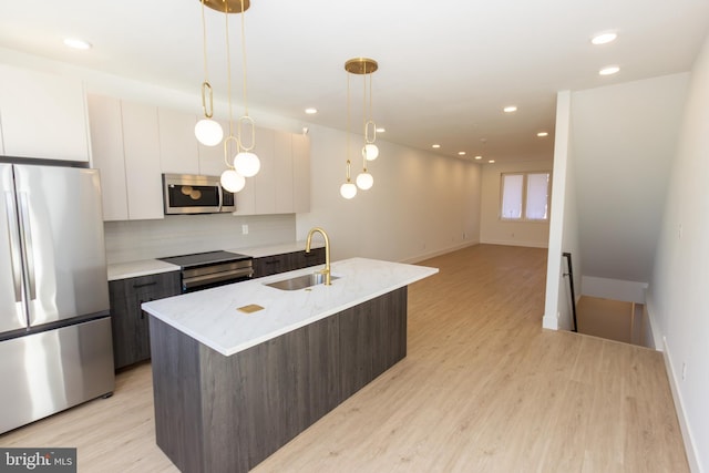 kitchen with light wood finished floors, modern cabinets, appliances with stainless steel finishes, and a sink