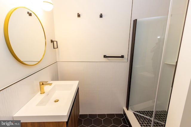 full bath featuring a wainscoted wall, tile patterned flooring, a shower stall, and vanity