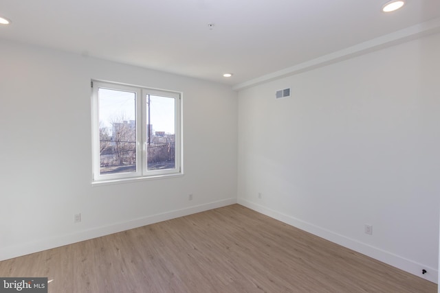 empty room with recessed lighting, visible vents, baseboards, and wood finished floors