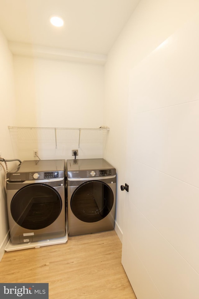 laundry area featuring washing machine and dryer, laundry area, baseboards, and wood finished floors