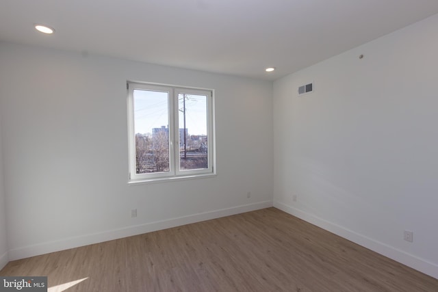 spare room featuring recessed lighting, wood finished floors, visible vents, and baseboards