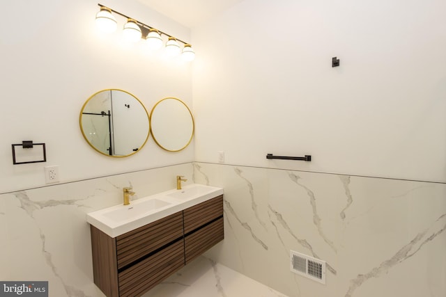 bathroom with a sink, visible vents, marble finish floor, wainscoting, and double vanity