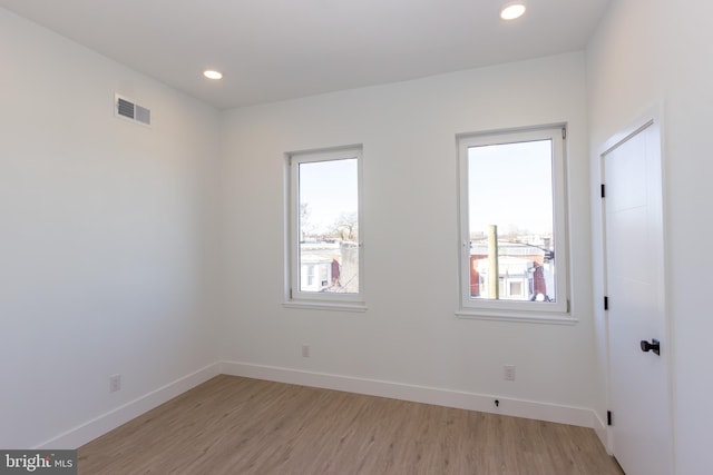 spare room featuring light wood-type flooring, visible vents, baseboards, and recessed lighting