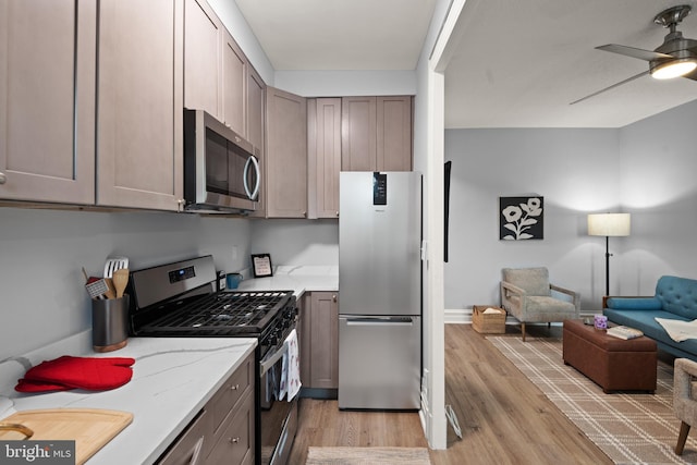 kitchen featuring stainless steel appliances, ceiling fan, and light hardwood / wood-style flooring