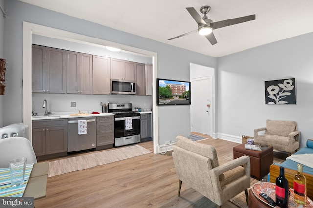 kitchen with ceiling fan, appliances with stainless steel finishes, sink, and light hardwood / wood-style floors