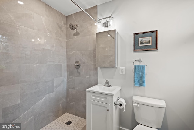 bathroom with vanity, toilet, and a tile shower