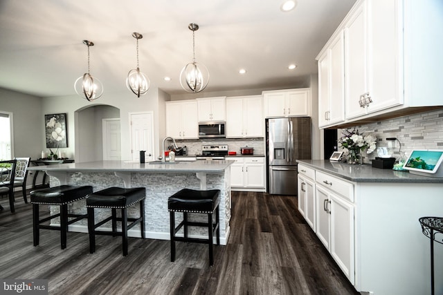 kitchen featuring sink, hanging light fixtures, appliances with stainless steel finishes, a kitchen island with sink, and white cabinets