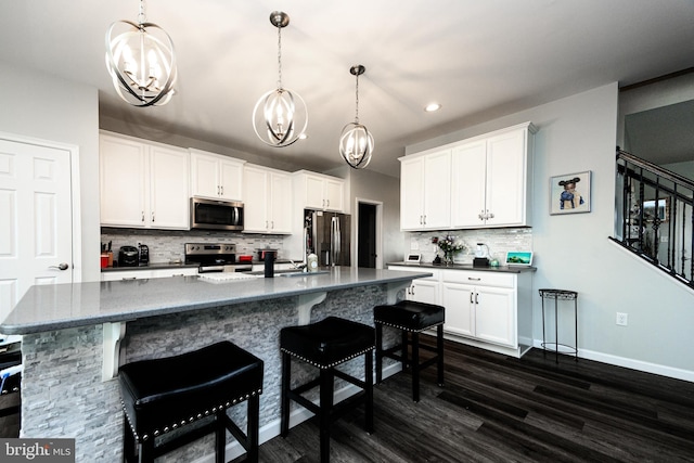 kitchen with stainless steel appliances, white cabinets, and decorative light fixtures