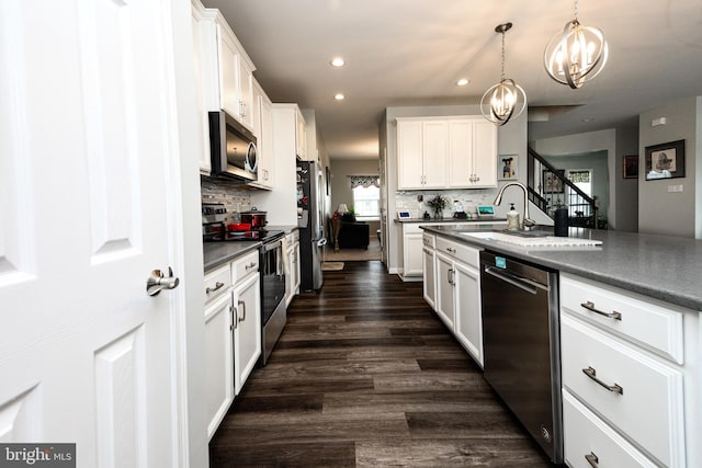 kitchen with appliances with stainless steel finishes, dark hardwood / wood-style floors, white cabinets, and decorative light fixtures