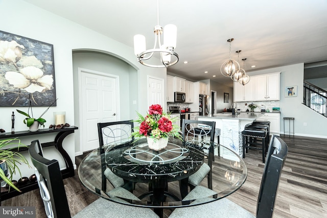 dining space featuring hardwood / wood-style flooring, sink, and a chandelier