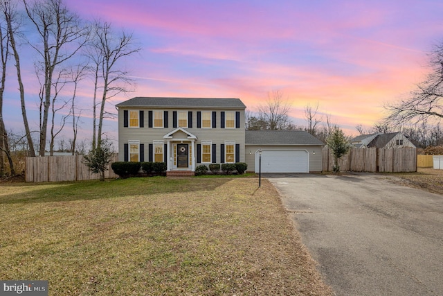 colonial inspired home featuring a garage and a yard