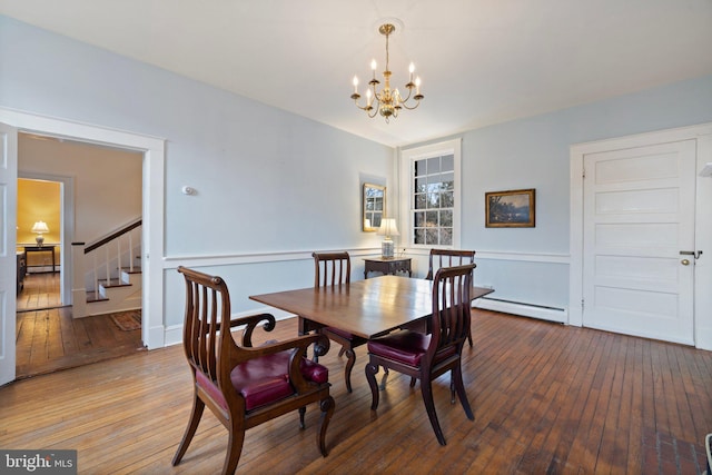 dining space featuring wood-type flooring, a baseboard heating unit, and an inviting chandelier