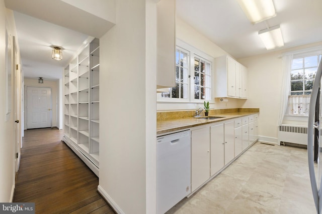 kitchen with radiator heating unit, a baseboard radiator, sink, white cabinets, and white dishwasher