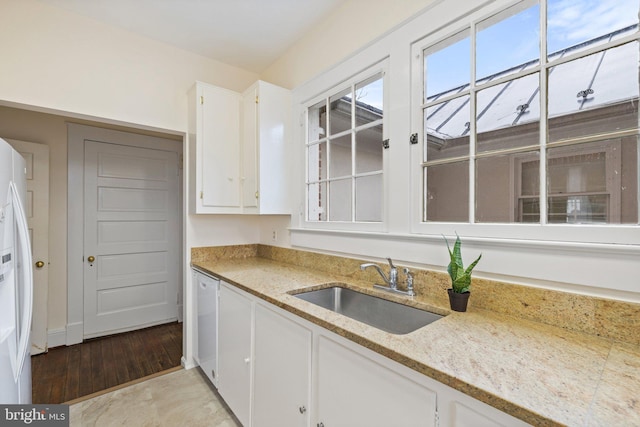 kitchen with sink, white appliances, light stone countertops, light hardwood / wood-style floors, and white cabinets