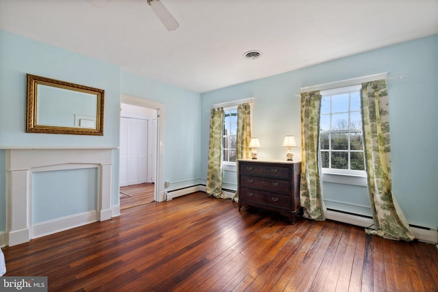 interior space featuring dark hardwood / wood-style flooring, a baseboard heating unit, a fireplace, and ceiling fan