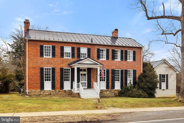 colonial-style house featuring a front yard and central air condition unit