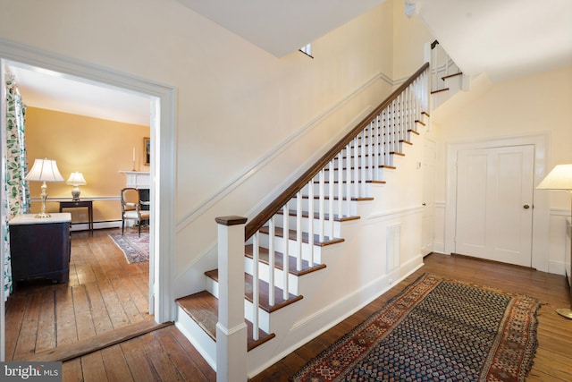 stairway with hardwood / wood-style floors and a baseboard heating unit