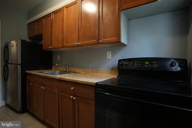 kitchen with stainless steel fridge, black range with electric stovetop, light tile patterned flooring, and sink