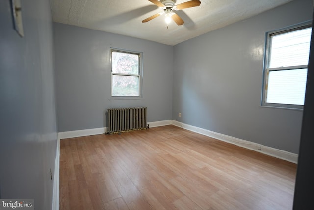 spare room featuring radiator, a textured ceiling, ceiling fan, and light hardwood / wood-style flooring