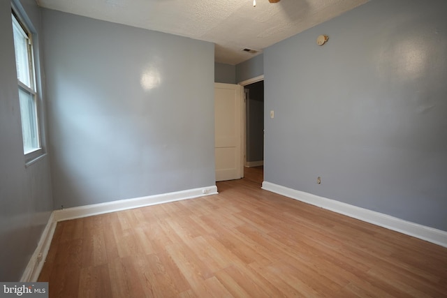 unfurnished room featuring ceiling fan, a textured ceiling, and light wood-type flooring