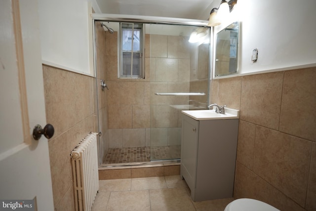 bathroom with tile patterned flooring, tile walls, radiator heating unit, vanity, and an enclosed shower