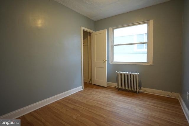 spare room with radiator heating unit, light hardwood / wood-style flooring, and a textured ceiling