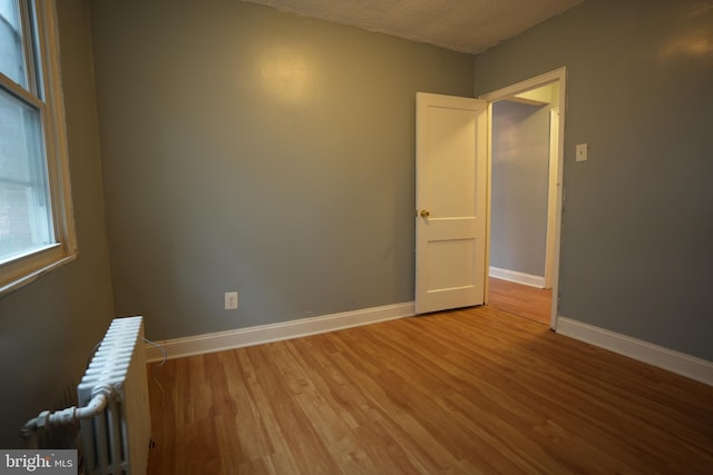 empty room featuring radiator heating unit and light hardwood / wood-style flooring