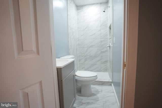 bathroom with vanity, toilet, and a tile shower