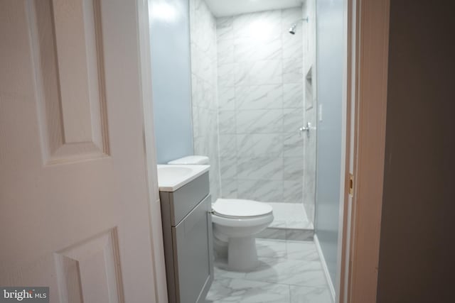 bathroom with vanity, tiled shower, and toilet