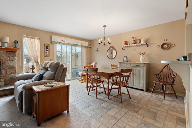 dining area featuring a stone fireplace and a chandelier