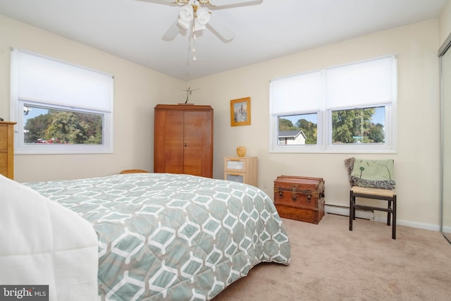 bedroom with baseboard heating, light carpet, and multiple windows