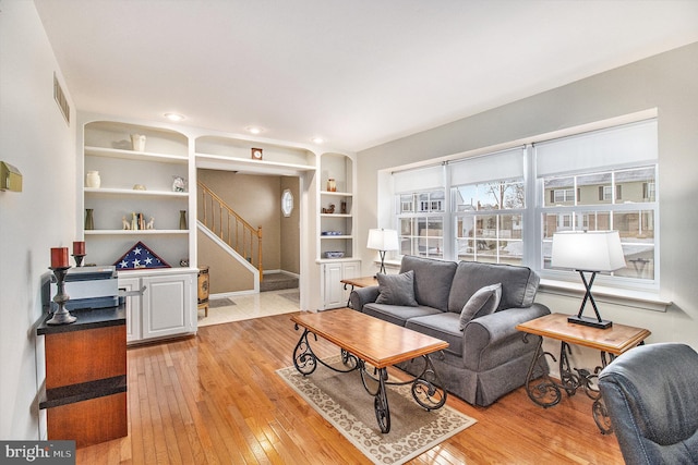 living room featuring built in features and light wood-type flooring