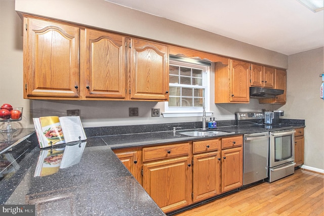 kitchen with appliances with stainless steel finishes, sink, and light wood-type flooring