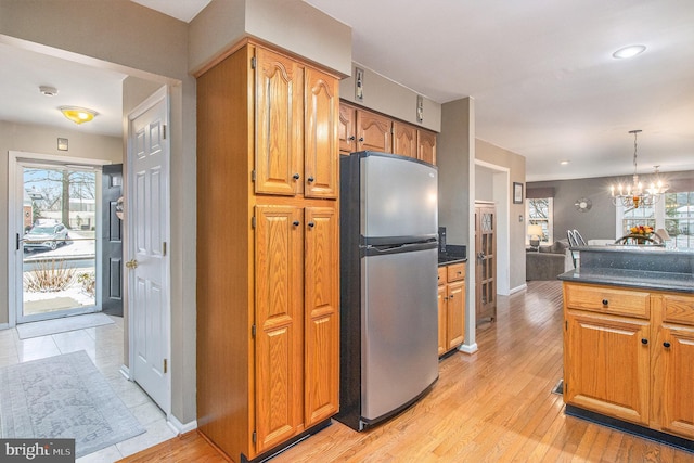 kitchen featuring light hardwood / wood-style flooring, hanging light fixtures, a notable chandelier, and stainless steel fridge