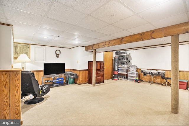 basement featuring carpet flooring, a paneled ceiling, and wood walls