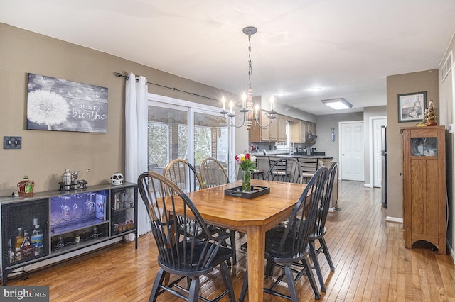 dining space with an inviting chandelier and light hardwood / wood-style floors