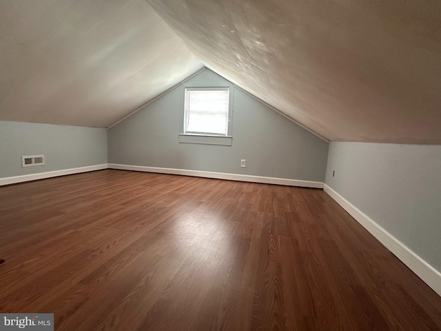 bonus room with lofted ceiling, dark wood-style floors, baseboards, and visible vents