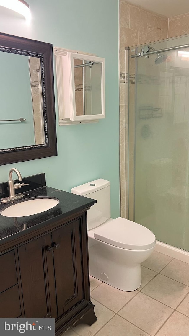 bathroom with toilet, a shower stall, vanity, and tile patterned floors